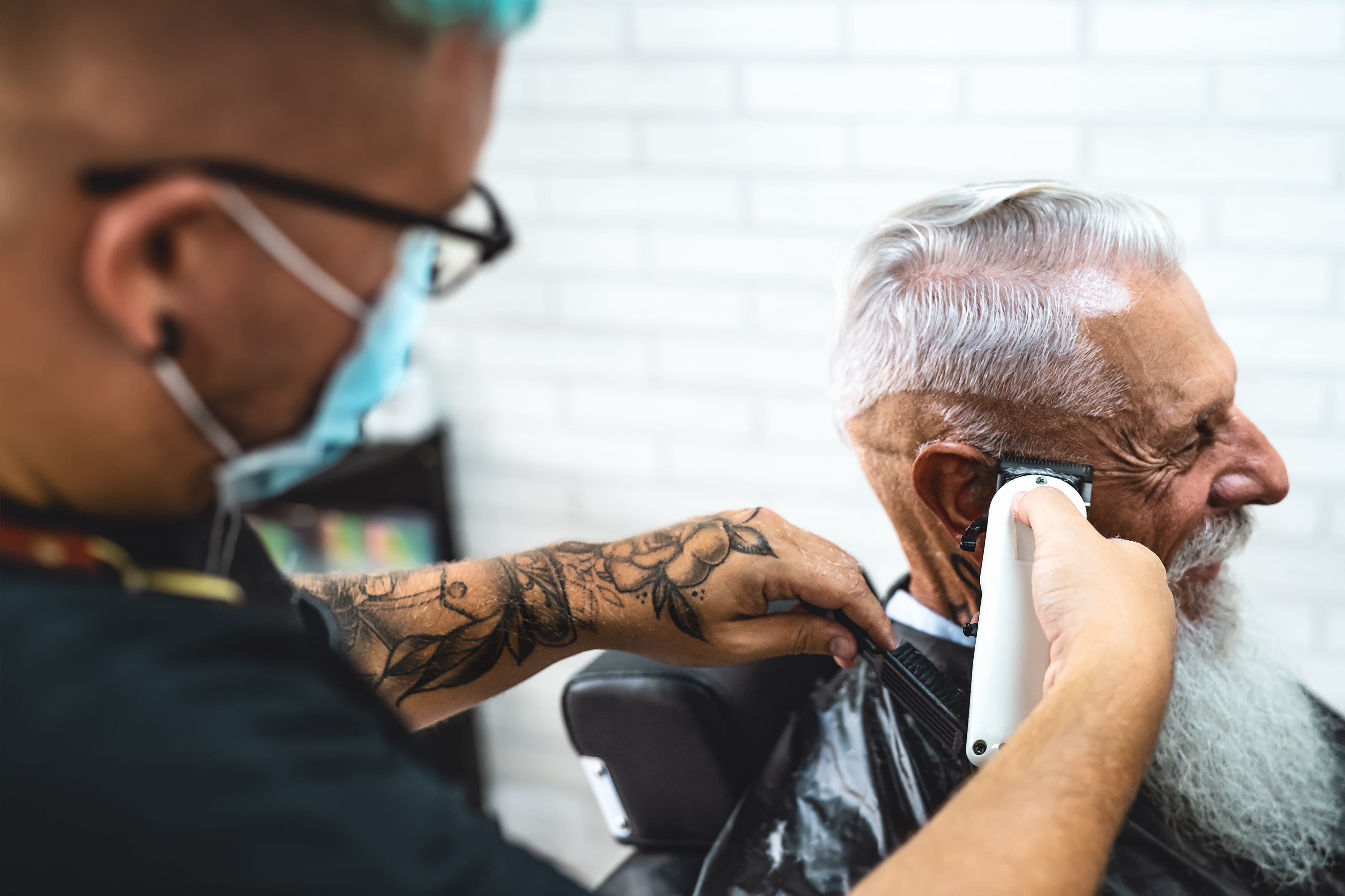 Coiffeur coupant les cheveux d'un client senior
